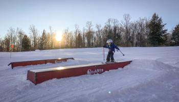 A person skiing down a terrain park on a ski mountain