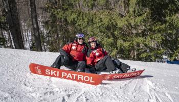 2 ski patrol sitting on the mountain